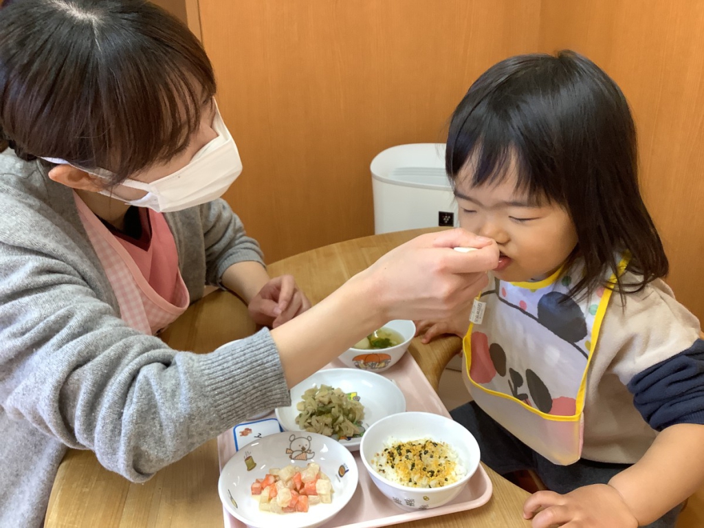 食事をする子どもと手伝う看護師