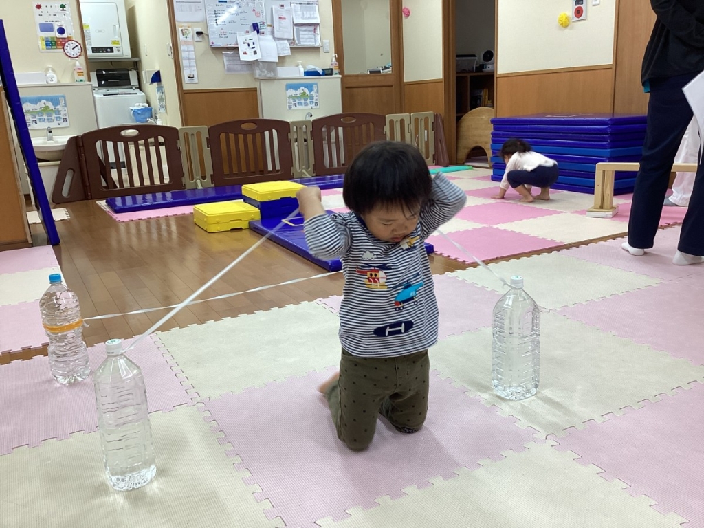 5月運動プログラムの様子(２歳児：ゴム跨ぎ)