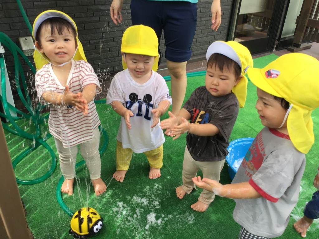 スプリンクラーで水に触れる子ども達