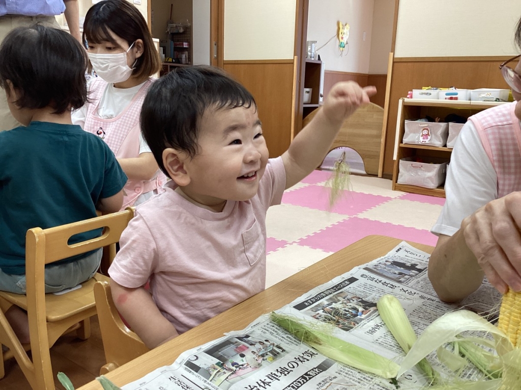 とうもろこしのひげを嬉しそうに触る園児