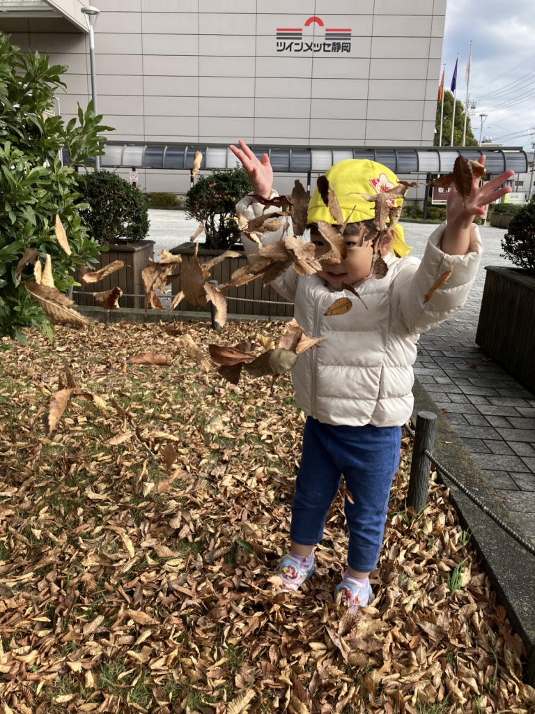 落ち葉で遊ぶ2歳児