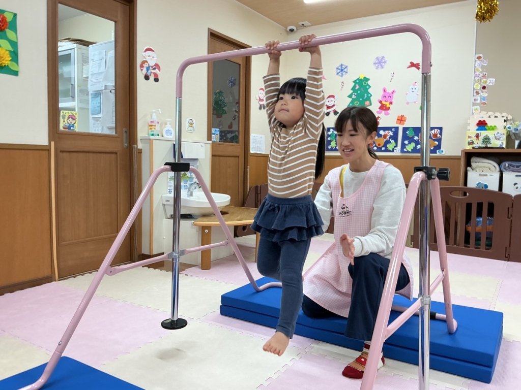 鉄棒にぶら下がる2歳児